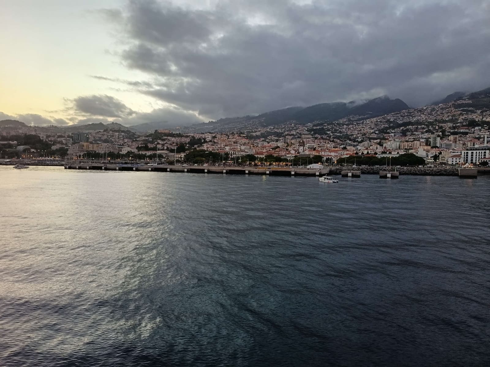 The breakwater at Funchal marina at dusk with the coastline in silhouette