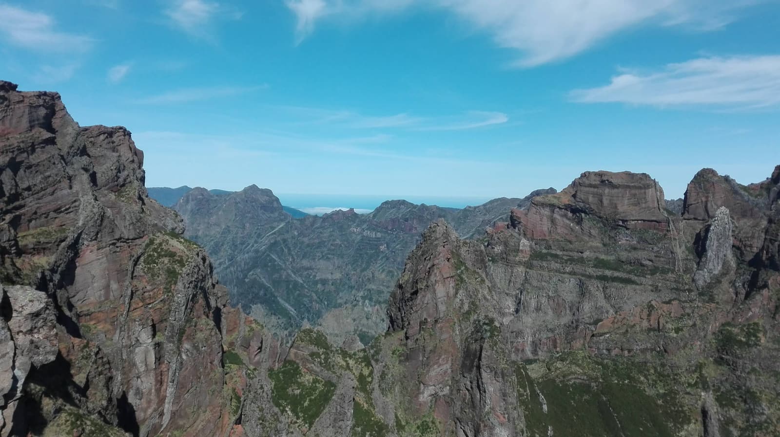 Sharp reddish volcanic peaks under a clear blue sky at Pico do Arieiro