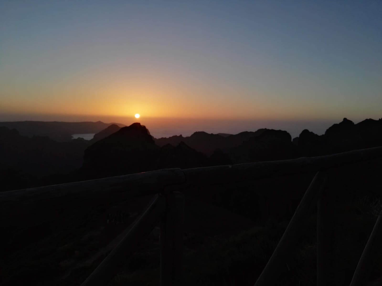 Mountain ridgeline at Pico do Arieiro glowing orange at sunset with the ocean visible beyond