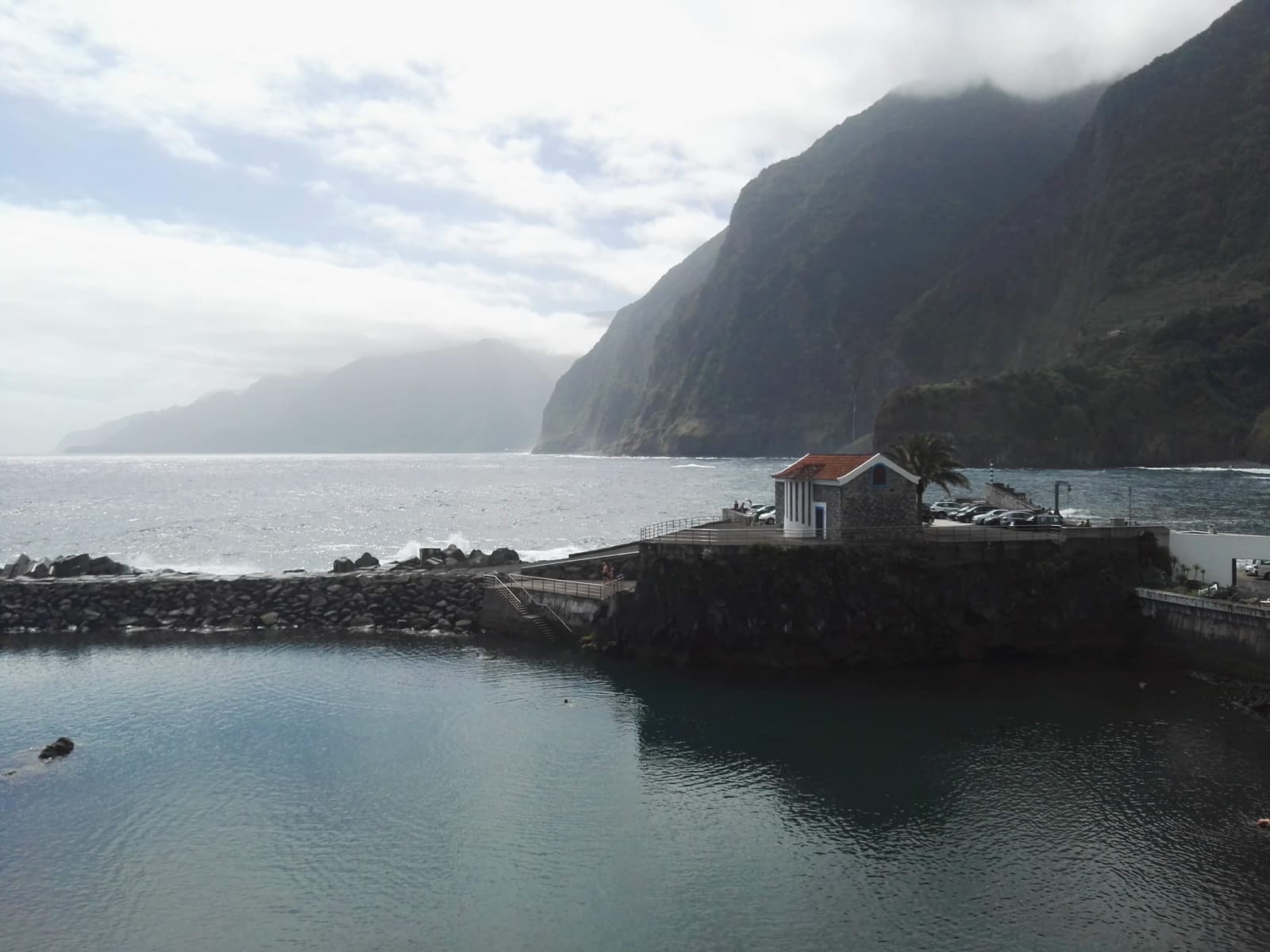 A small stone chapel on a rocky natural pool inlet on Madeira's north coast at Seixal, cliffs behind